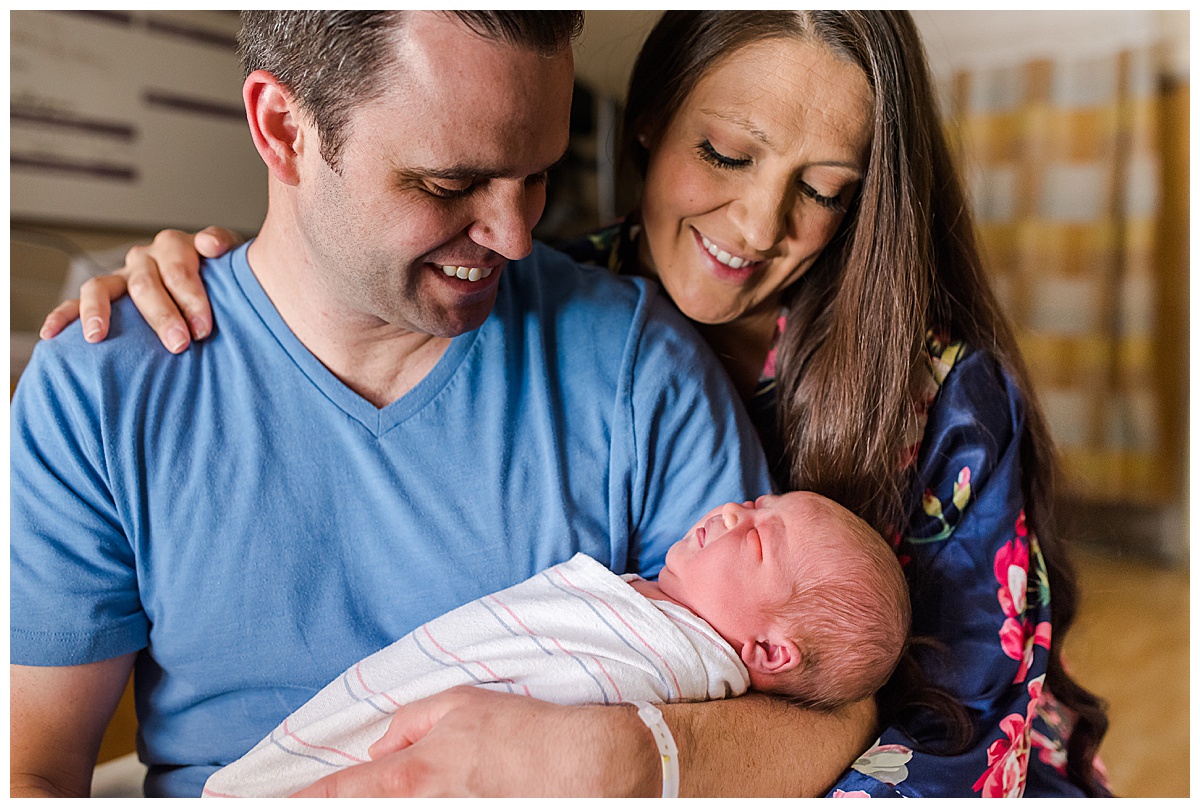 new parents in hospital room gazing adoringly at their newborn son