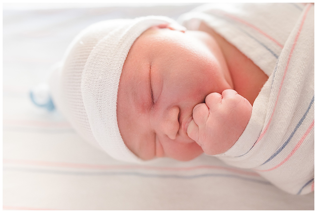 swaddled newborn baby sucking on his hand during Fresh 48 hospital newborn session