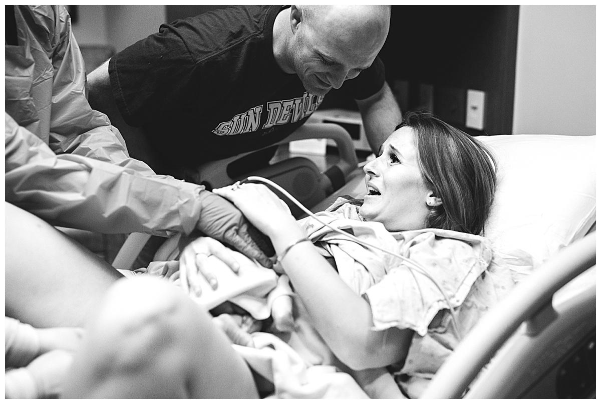 happy parents adoring newborn baby in delivery room