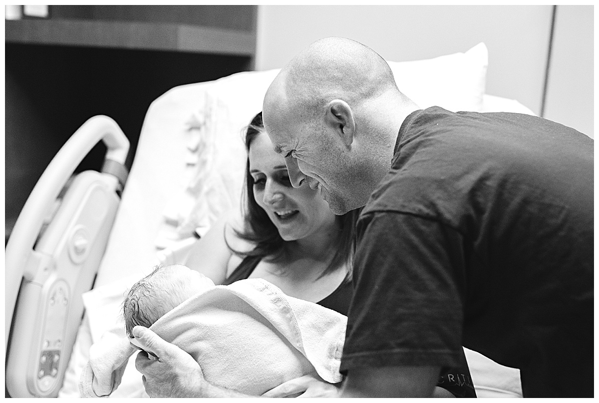 new parents smile at baby boy in delivery room
