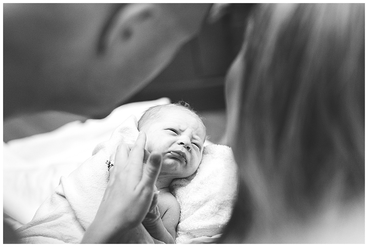 newborn baby boy looks at parents in delivery room