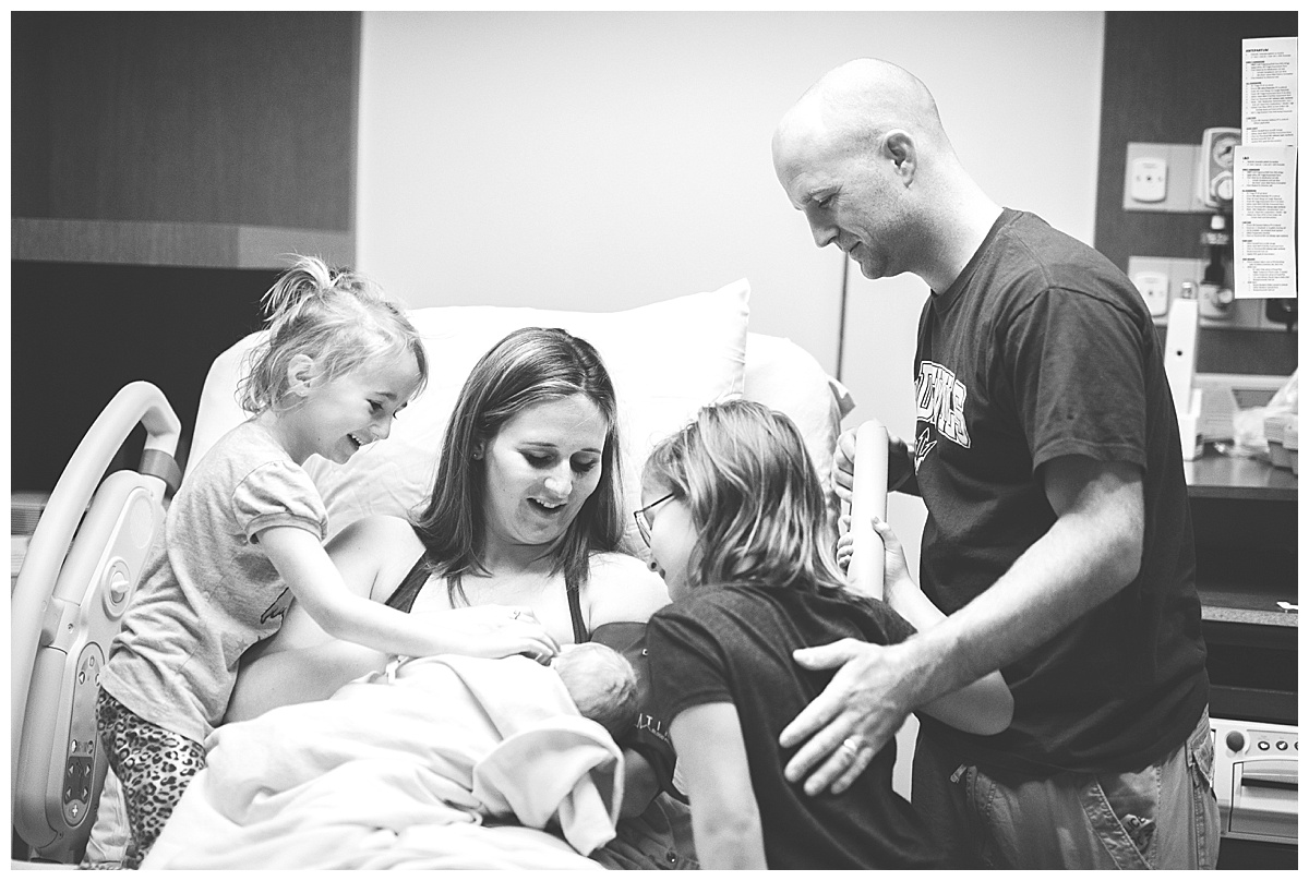 family gathers around newborn baby boy in delivery room