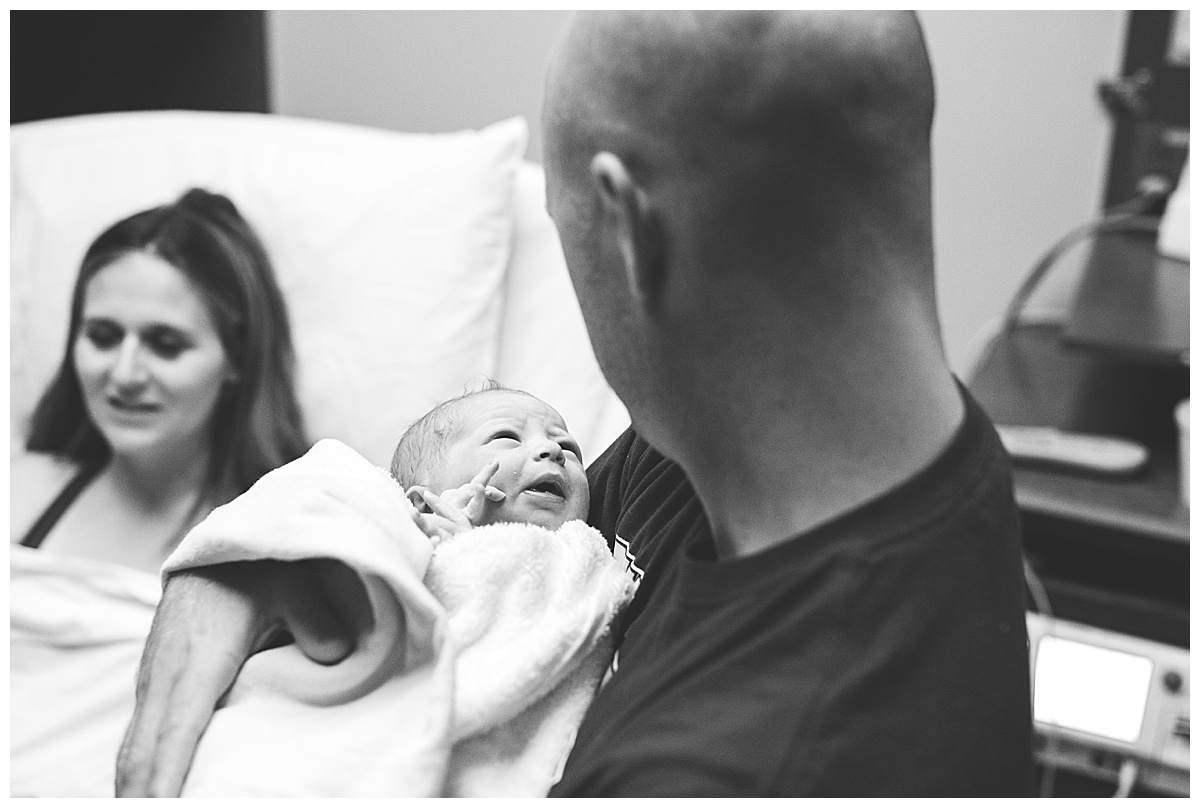 dad holds newborn baby boy in delivery room