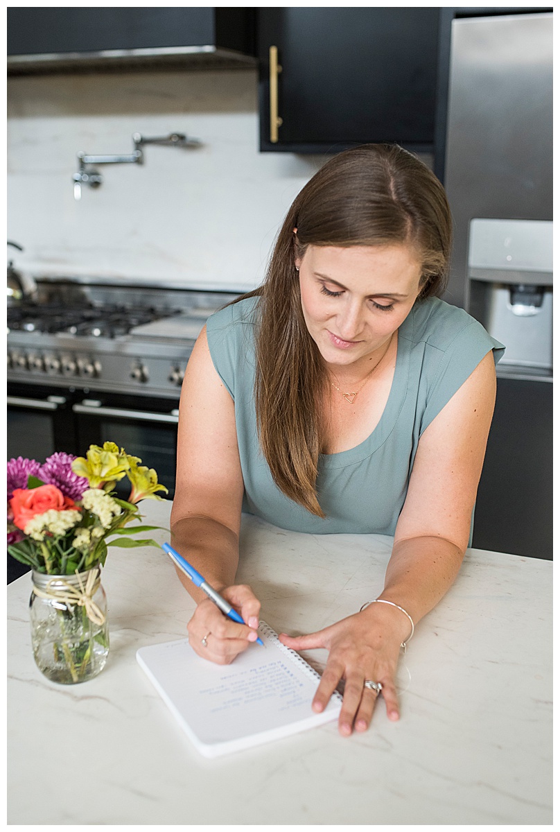 busy mom meal planning for her family using a pen and notebook