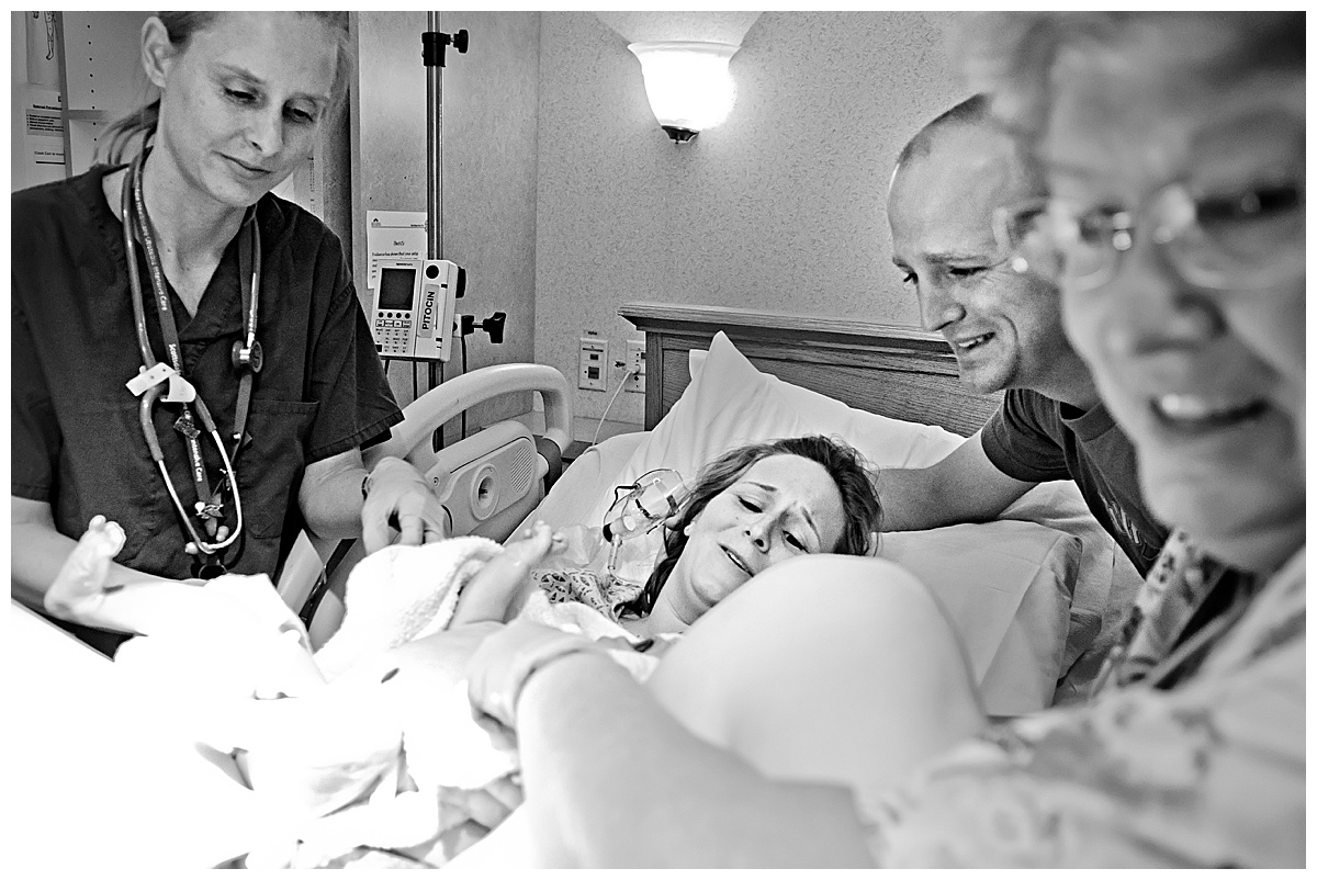 black and white image of mom and dad seeing their new baby boy for the first time in hospital delivery room