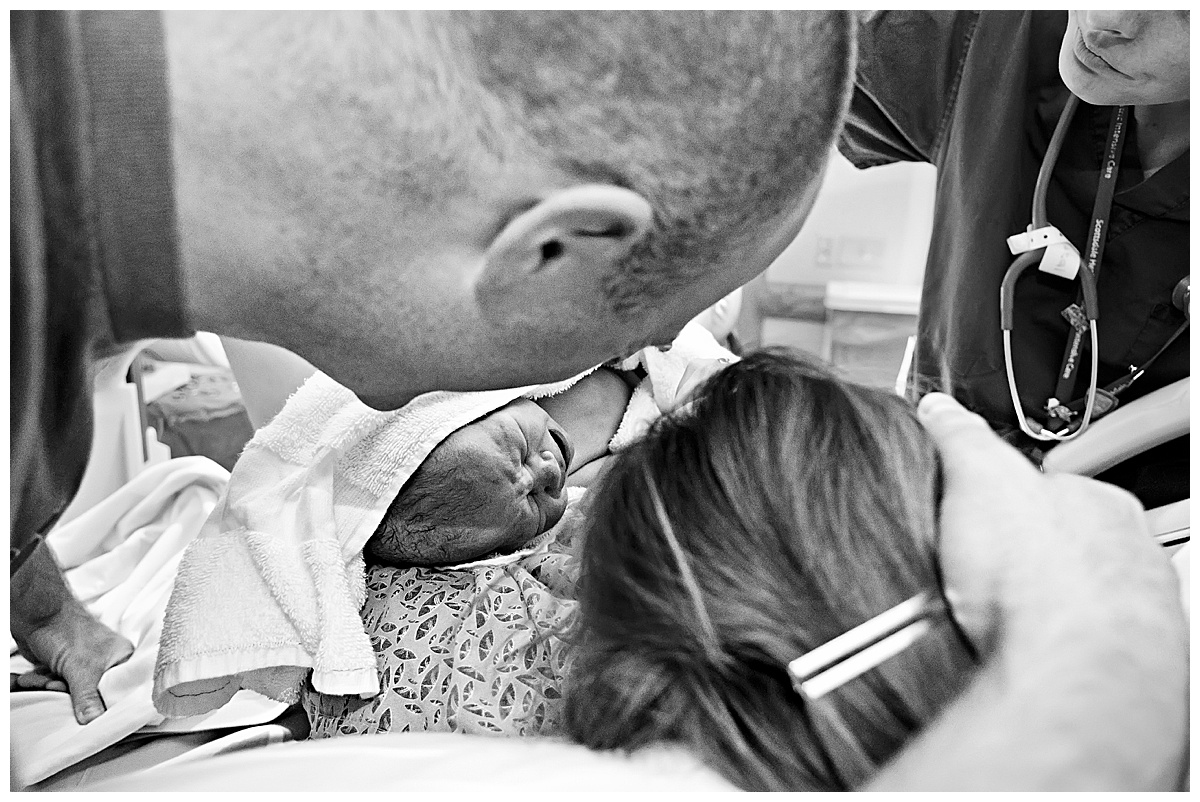 black and white image of mom and dad looking at brand new baby boy