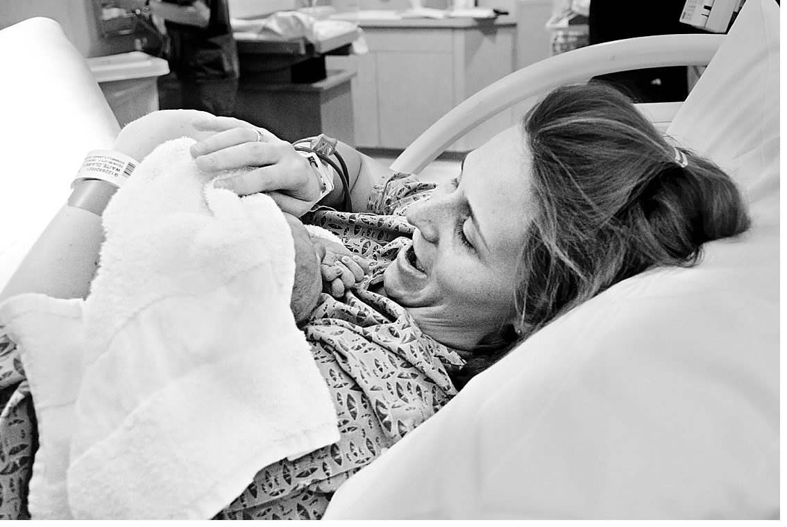 black and white image of mom greeting her newborn baby boy in hospital delivery room