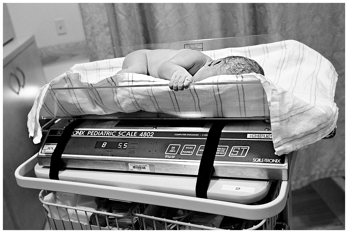 black and white image of newborn baby boy being weighed