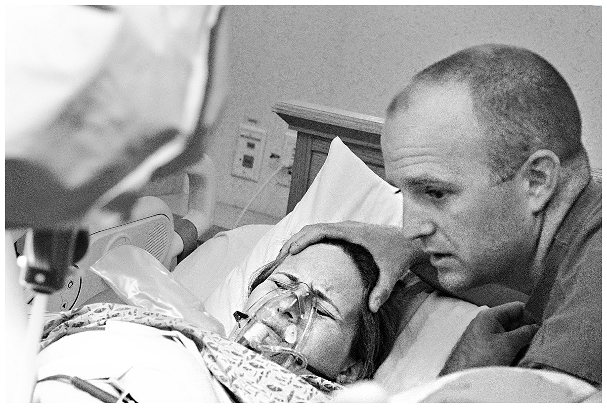 black and white photo of woman in labor pushing while wearing an oxygen mask