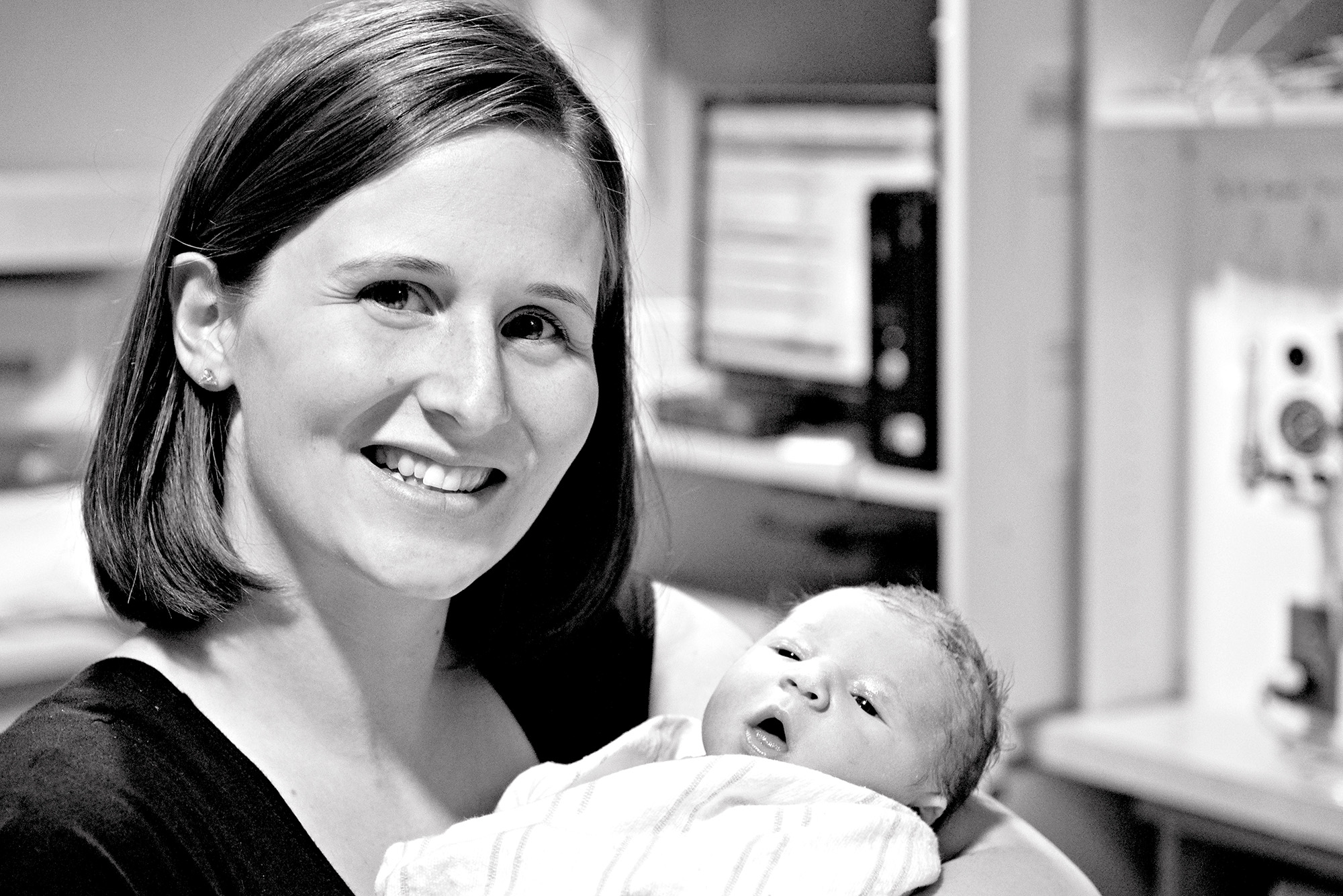 Black and white image of arizona birth photographer Claire Waite holding a newborn after photographing his birth