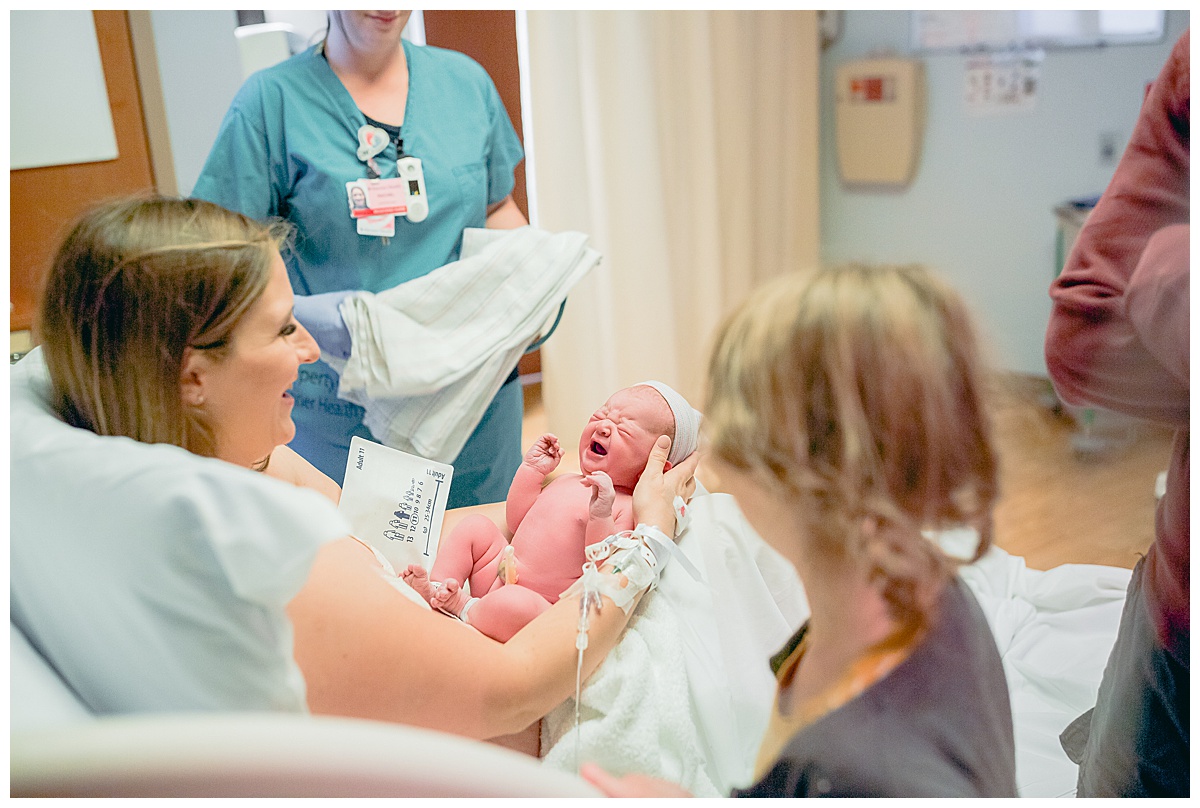 color image of Arizona birth photographer Claire Waite meeting her daughter in the delivery room at Banner Del Webb Hospital