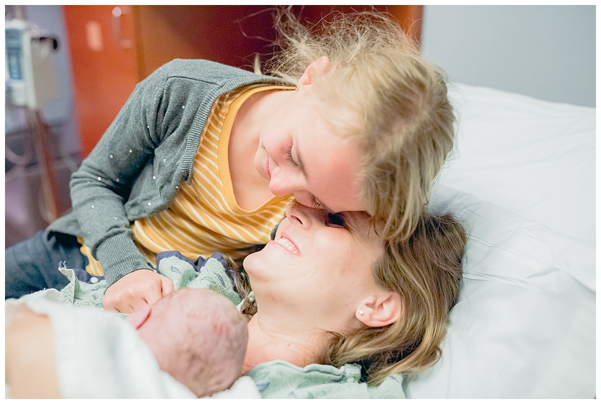 AZ birth photographer, Claire Waite, snuggles her 10 year old daughter and newborn in the delivery room at Banner Del Webb Hospital
